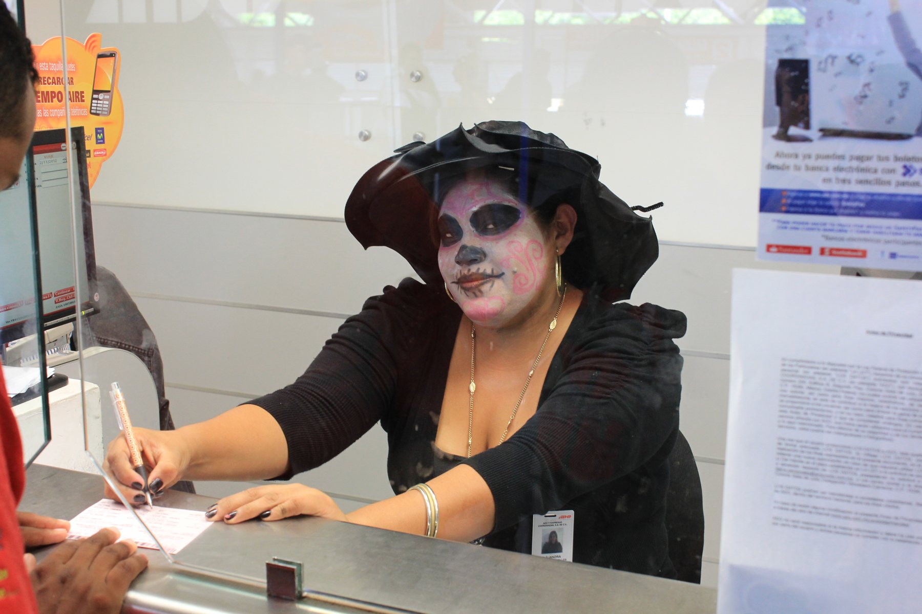 Ticket agent in Day of the Dead make-up serving a customer, Mexico